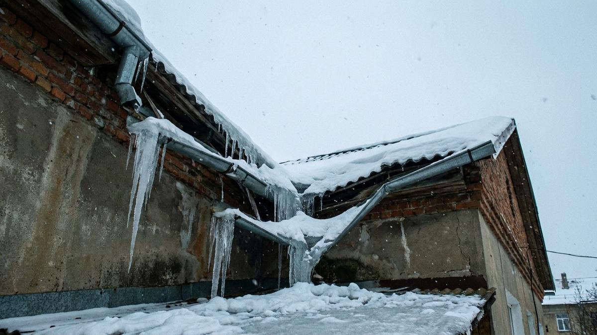 雪害で破損したアパートの雨樋と屋根
