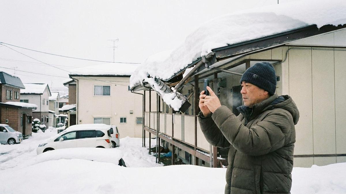 雪害後に建物を撮影して保険申請を準備するオーナー