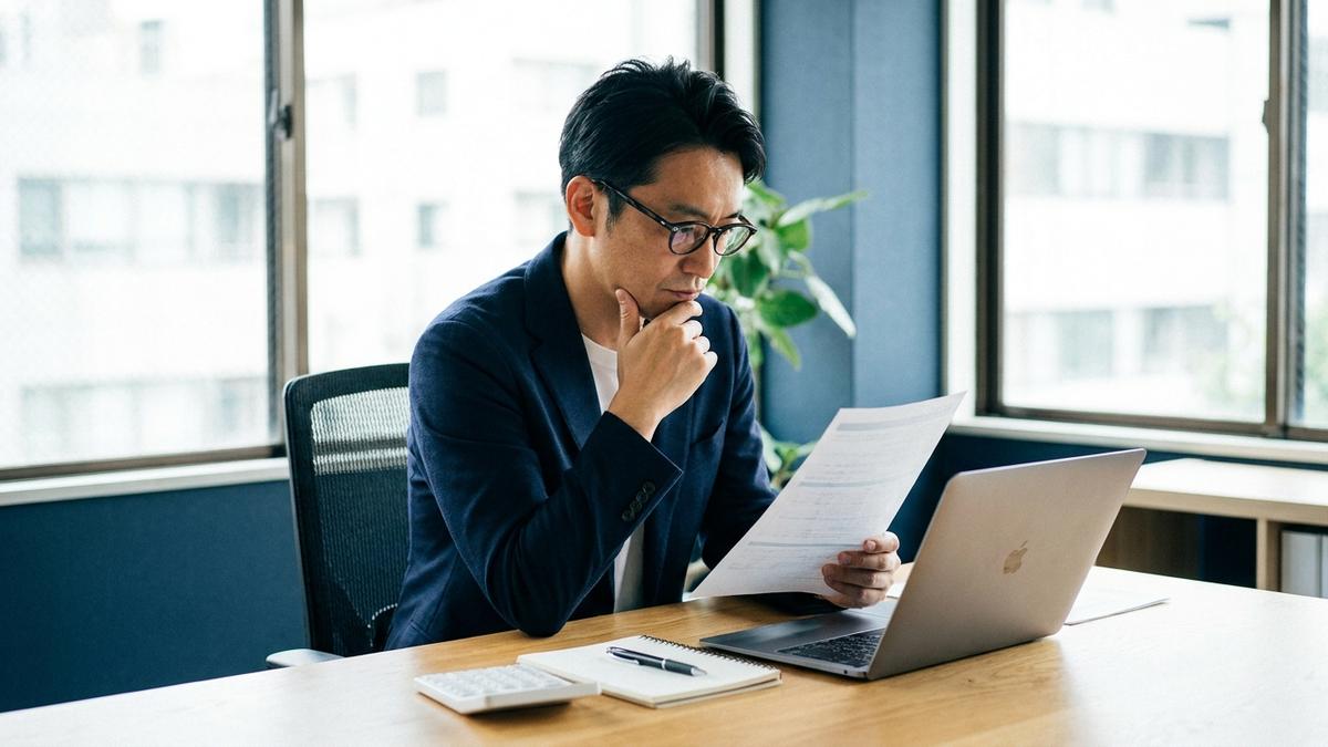 保険と資産運用の基礎知識をイメージした資料を見比べる男性の写真